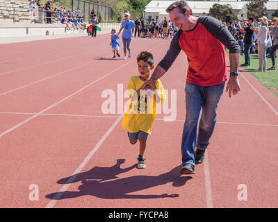 Un père tient la main de son fils handicapé dans une course à la tenue des Jeux olympiques spéciaux du sud de la Californie à Santa Barbara, CA. Banque D'Images