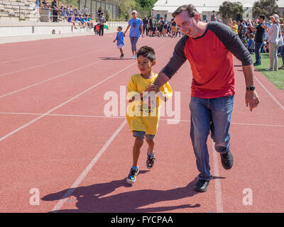 Un père tient la main de son fils handicapé dans une course à la tenue des Jeux olympiques spéciaux du sud de la Californie à Santa Barbara, CA. Banque D'Images