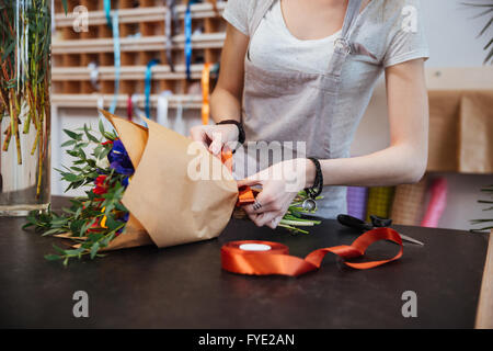 Mains de jeune femme debout et faire fleuriste bouquet de fleurs en boutique Banque D'Images