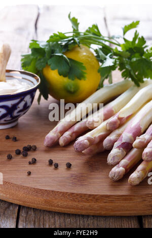 Asperges pelées et ingrédients pour une sauce sur planche de bois, selective focus Banque D'Images