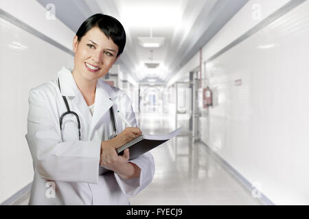 Brunette femme médecin de garde à white hospital corridor, PH.D. Banque D'Images