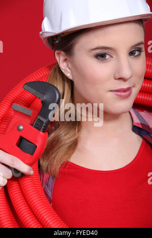 Plombier femme en rouge avec un tuyau rouge et la clé Banque D'Images