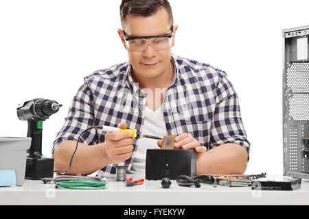 Les jeunes PC technicien travaillant avec fer à souder et la réparation d'un ordinateur isolé sur fond blanc Banque D'Images