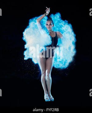 Jeune femme sautant en bleu nuage de poudre sur fond noir Banque D'Images