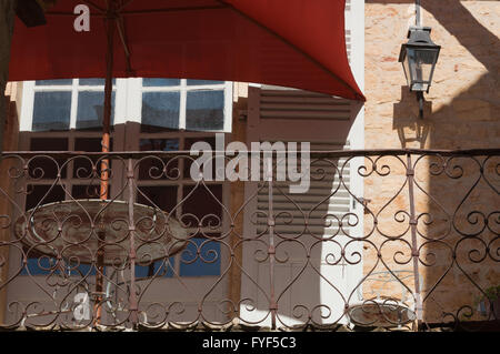 Parasol rouge et la rouille metal table et chaise sur le balcon de la chambre française en side alley dans la région de la Dordogne Banque D'Images