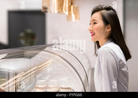 Commerçant en face de display cabinet in bakery Banque D'Images