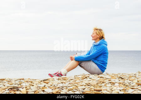 Femme assise sur la plage et regarde dans la distance Banque D'Images