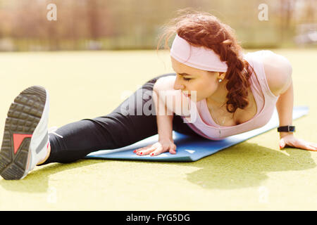 Jeune femme souple doing stretching sur Tapis de fitness. Fille sportive beauté étirer ses jambes après entraînement Banque D'Images