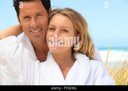 Heureux couple portant des robes à la plage Banque D'Images
