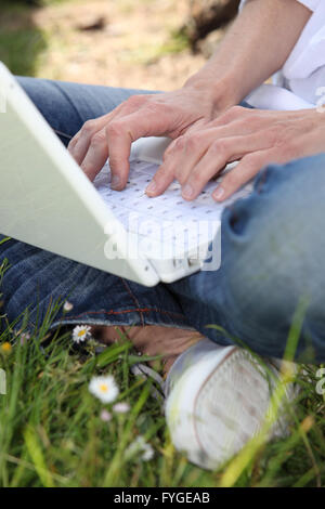 Close-up of woman sat cross legged typing on laptop computer Banque D'Images