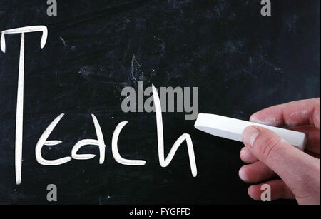 Enseigner à la main avec craie blanche sur un tableau noir Banque D'Images