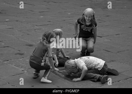 Les enfants sur le site dans un égout, Piazza Signorelli, Cortona, Arezzo, Italie Banque D'Images