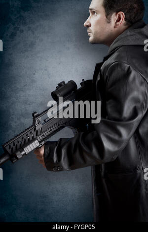 Homme aux longues veste en cuir et un fusil d'assaut
