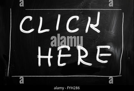 Cliquez ici à la main avec craie blanche sur un tableau noir Banque D'Images