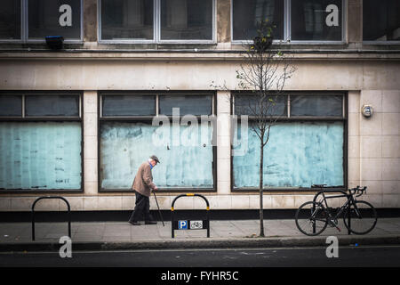 Vieil homme dans une rue de Londres à l'extérieur atelier fermé Banque D'Images