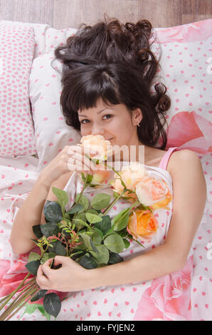 Girl enjoying parfum des fleurs, au lit Banque D'Images