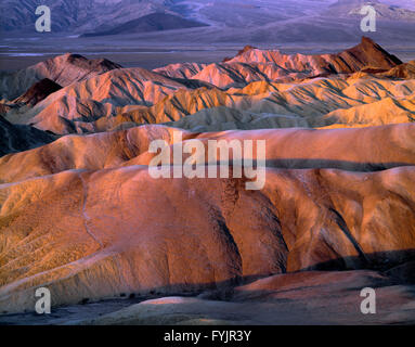 États-unis, Californie, Death Valley National Park, le lever du soleil la lumière sur les collines de mudstone érodés, vue ouest de Zabriskie Point. Banque D'Images