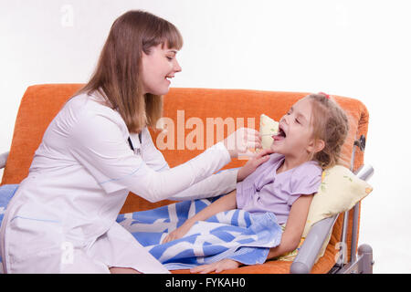 Le médecin examine le malade de la gorge petite fille au lit Banque D'Images