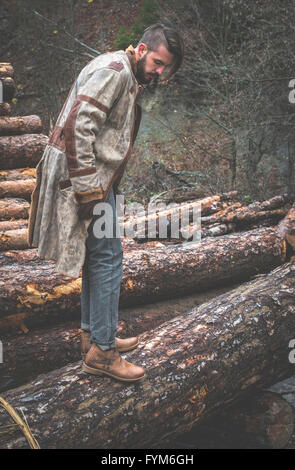 Les jeunes hommes sur des rondins dans la forêt. Cuir et jeans. La mode en plein air Banque D'Images