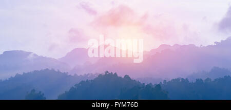 Lever du soleil depuis le bord de Foggy Mountain après de pleuvoir dans la nuit. Les couleurs du ciel et des montagnes changement à violet et bleu. Banque D'Images