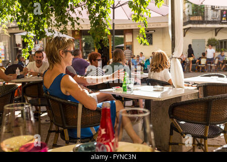 Une femme les vacanciers se détendre et regarder le monde passer dans un café de la chaussée, Lourmarin, Vaucluse, PACA, France Banque D'Images