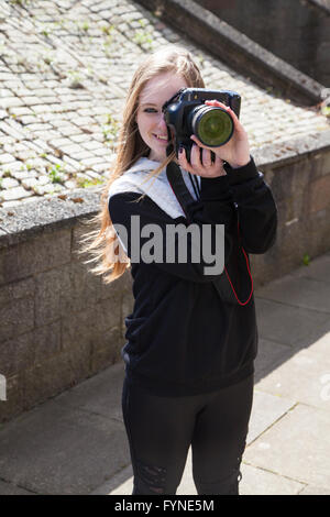 Une femme photographe pointant son appareil photo numérique vers l'observateur. Banque D'Images