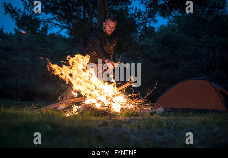 L'homme allume un feu dans la cheminée dans la nature la nuit. Banque D'Images