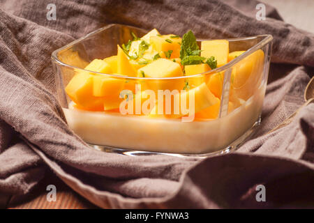 Dessert au lait servi avec des feuilles de menthe hachée et mangue Banque D'Images