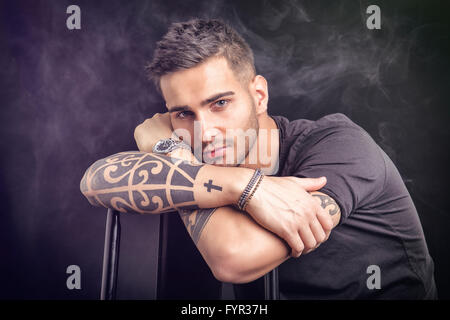 Beau et élégant jeune homme avec t-shirt noir. Tatouages frais sur les armes Banque D'Images