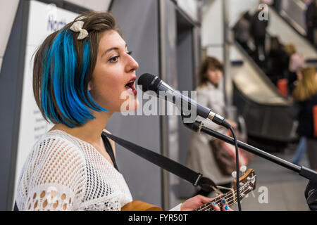 Mino Jazz chante et joue le ukulele comme elle busks pour les passagers passant par la station de métro Waterloo, Londres. Elle est Banque D'Images