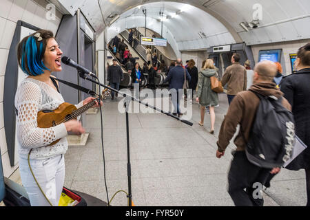 Mino Jazz chante et joue le ukulele comme elle busks pour les passagers passant par la station de métro Waterloo, Londres. Elle est Banque D'Images