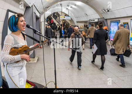 Mino Jazz chante et joue le ukulele comme elle busks pour les passagers passant par la station de métro Waterloo, Londres. Elle est Banque D'Images