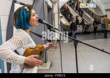 Mino Jazz chante et joue le ukulele comme elle busks pour les passagers passant par la station de métro Waterloo, Londres. Elle est Banque D'Images