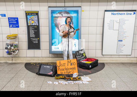 Mino Jazz chante et joue le ukulele comme elle busks pour les passagers passant par la station de métro Waterloo, Londres. Elle est Banque D'Images