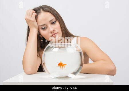 Jeune fille en colère à la recherche de poissons rouges dans un bocal Banque D'Images