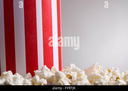 Libre blanc rayé rouge boîte contenant debout avec popcorn, low angle, fond gris Banque D'Images