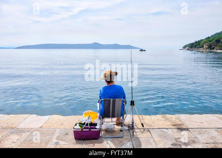 Homme assis seul sur une pêche pier Banque D'Images
