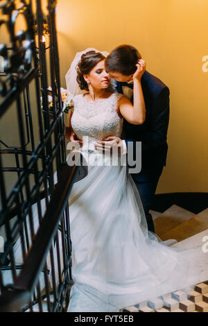 Couple de jeunes mariés nouvellement debout à l'escalier Banque D'Images