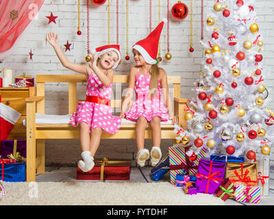 Deux funny girls niaises assis sur un banc dans un paramètre de Noël Banque D'Images