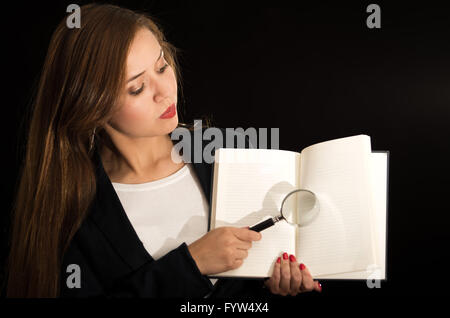 Jeune brunette woman holding up caméra livre ouvert et loupe pages ci-dessus Banque D'Images