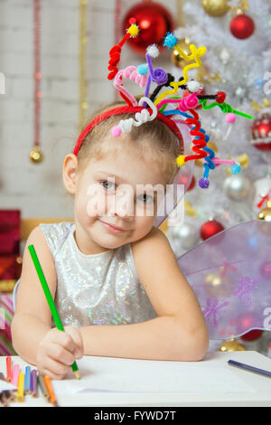 Fille avec un jouet sur la tête d'artifice attire l'crayon sur une feuille Banque D'Images