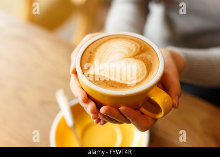 Lady's hands holding cup avec sth forme coeur Banque D'Images