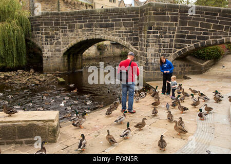 Royaume-uni, Angleterre, dans le Yorkshire, Calderdale Hebden Bridge, les canards d'alimentation des jeunes enfants en dessous de l'ancien pont à cheval Banque D'Images