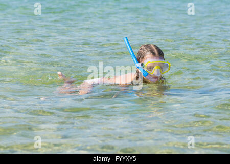 Girl flotte au-dessus de l'eau avec masque et tuba Banque D'Images