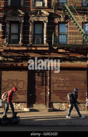 Sur le chemin de l'école, deux enfants passent devant un magasin fermé à New York. Immeuble en briques anciennes sur Rivington Street, Lower East Sid Banque D'Images