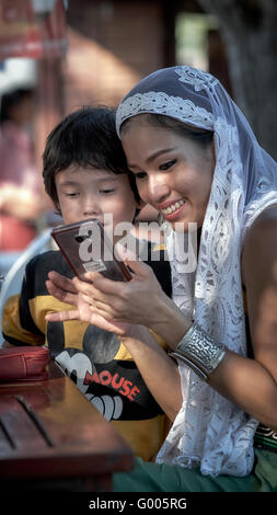 Mère et enfant regardant les images du téléphone. Femme asiatique souriante, heureuse, riante. Maternité Asie Banque D'Images