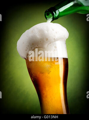 Verser la bière dans un verre sur fond vert Banque D'Images