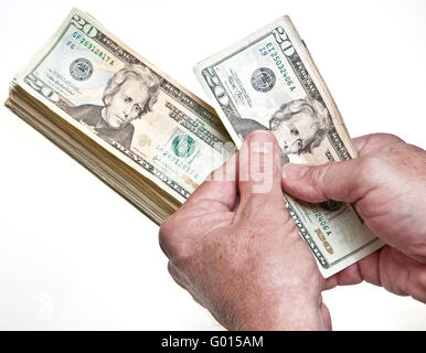 Older Man's hands comptant vingt dollars dans une pile sur fond blanc Banque D'Images