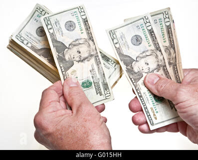 Older Man's hands comptant vingt dollars dans une pile sur fond blanc Banque D'Images