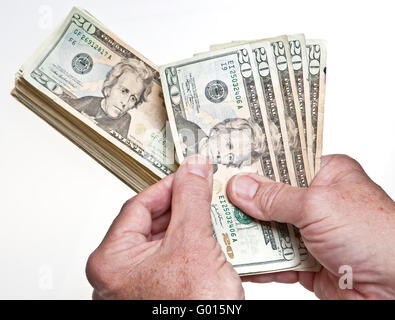 Older Man's hands comptant vingt dollars dans une pile sur fond blanc Banque D'Images